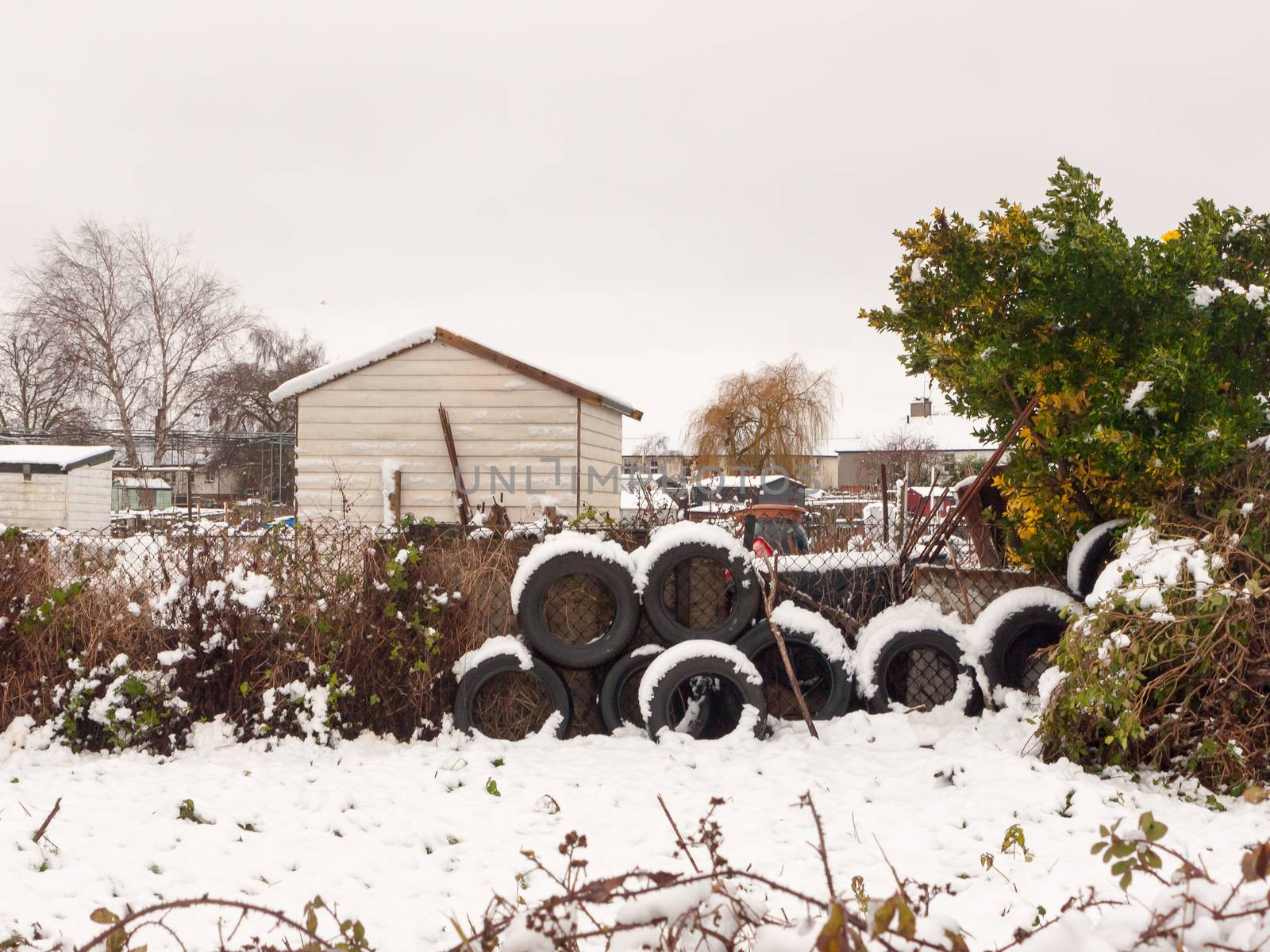 side of allotment scene winter close up snow december stack of tires; essex; england; uk