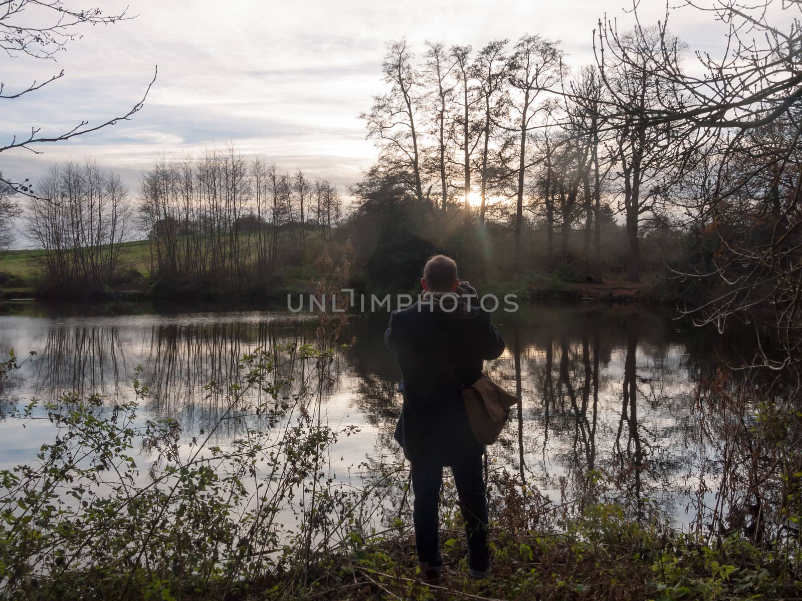 man standing in front of lake taking a picture with camera activ by callumrc