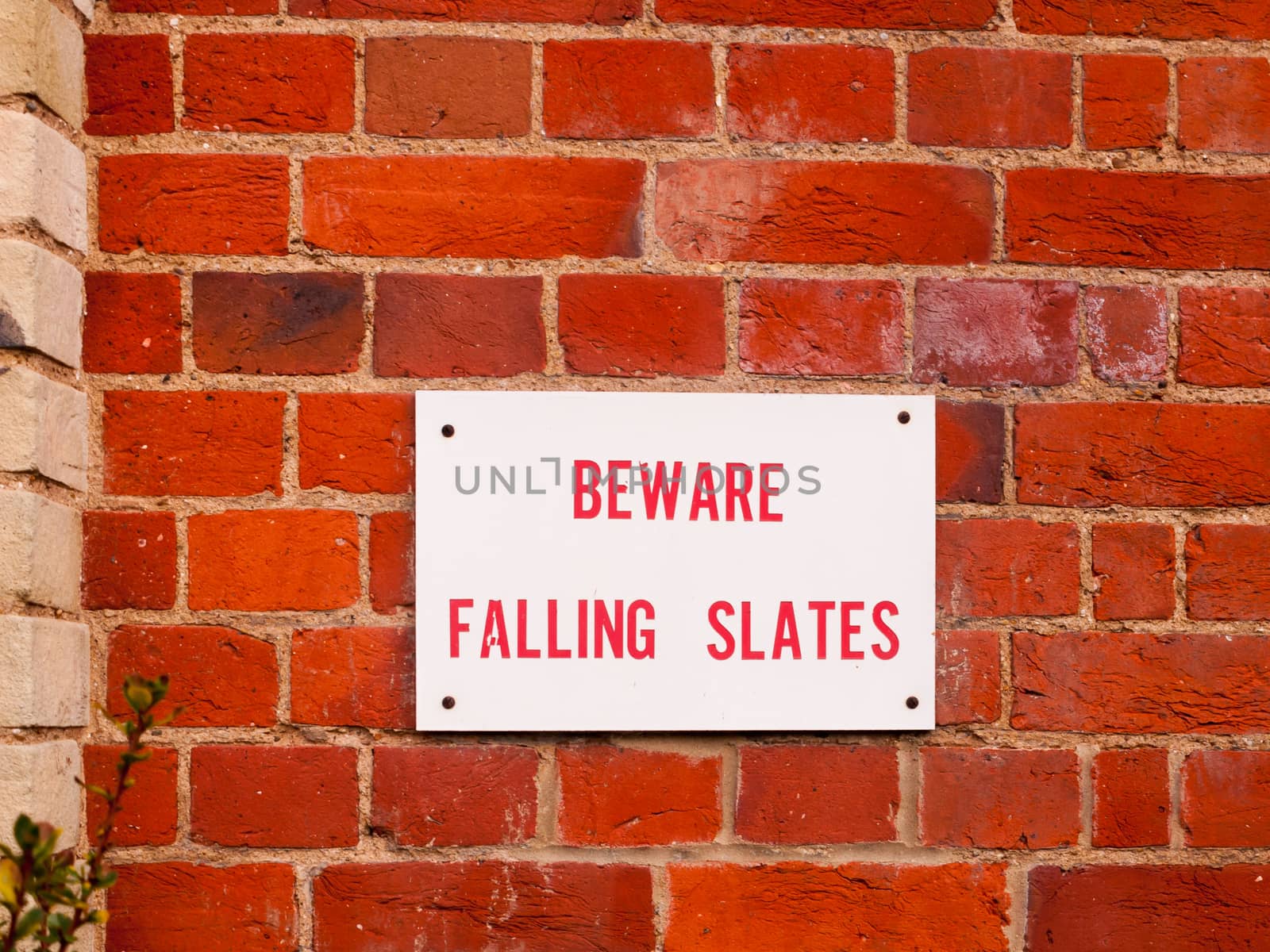 information sign on red brick wall beware falling slates; essex; england; uk