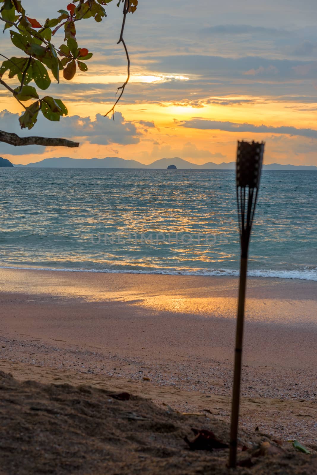 decorative torch on the sandy beach of Thailand and sunset on the sea