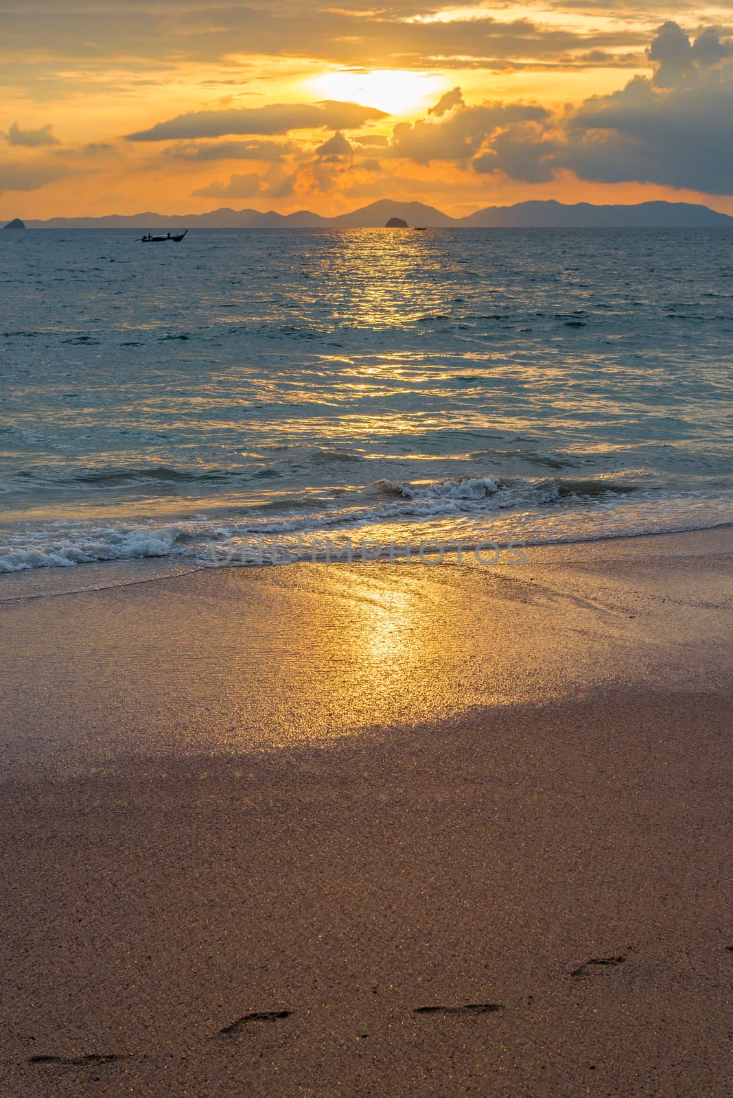 sandy beach, calm sea, cumulus clouds and beautiful orange sunset over the sea