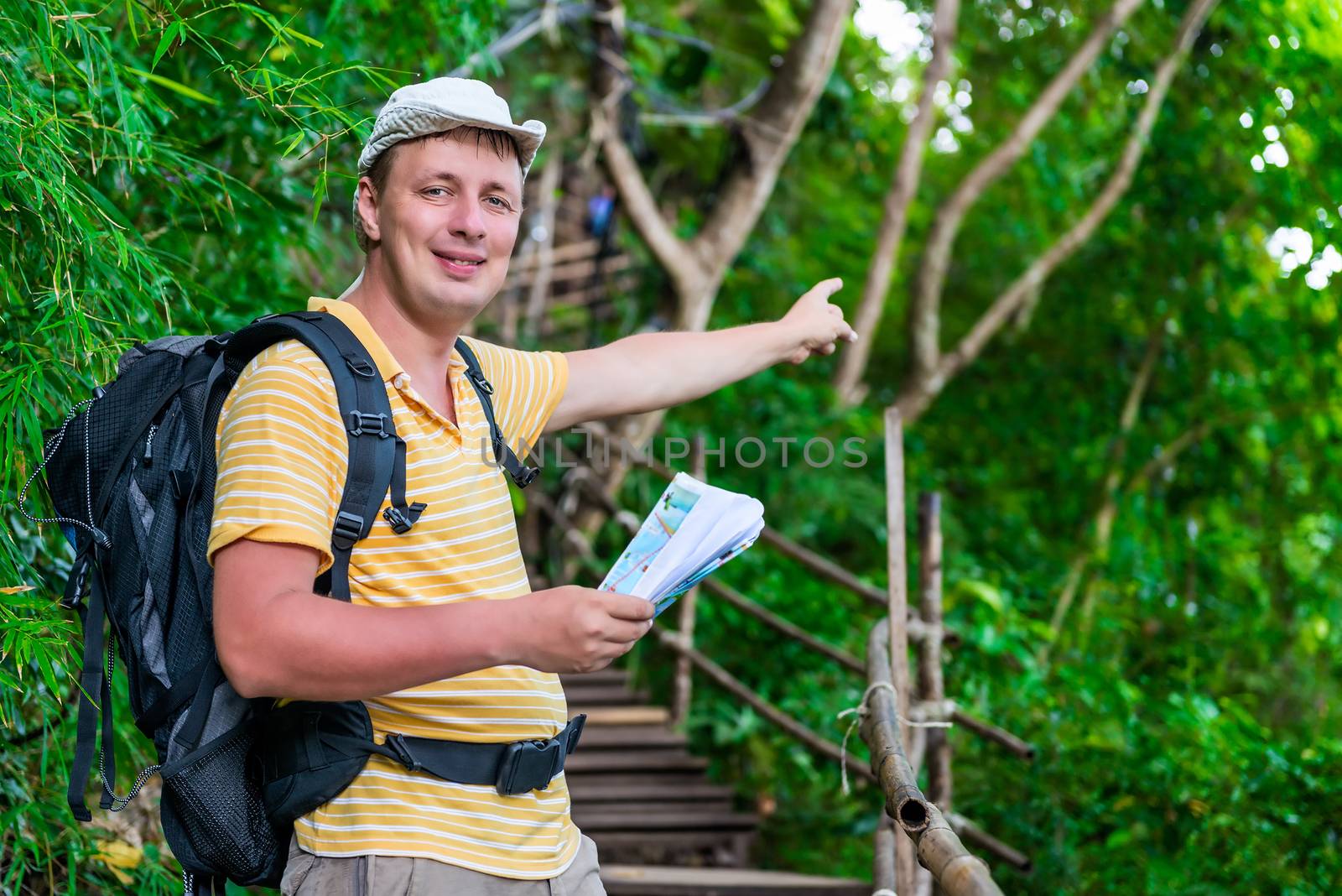 tourist with a backpack in the Asian jungle in the hike shows the direction of the route