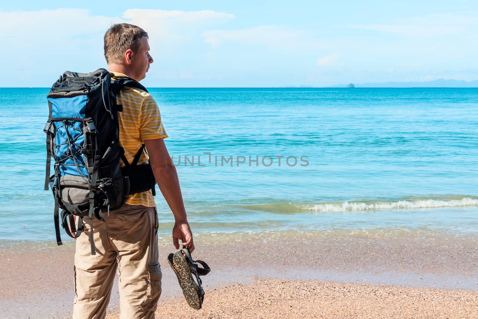 tourist with a backpack spends vacation on the beach, admires a beautiful view