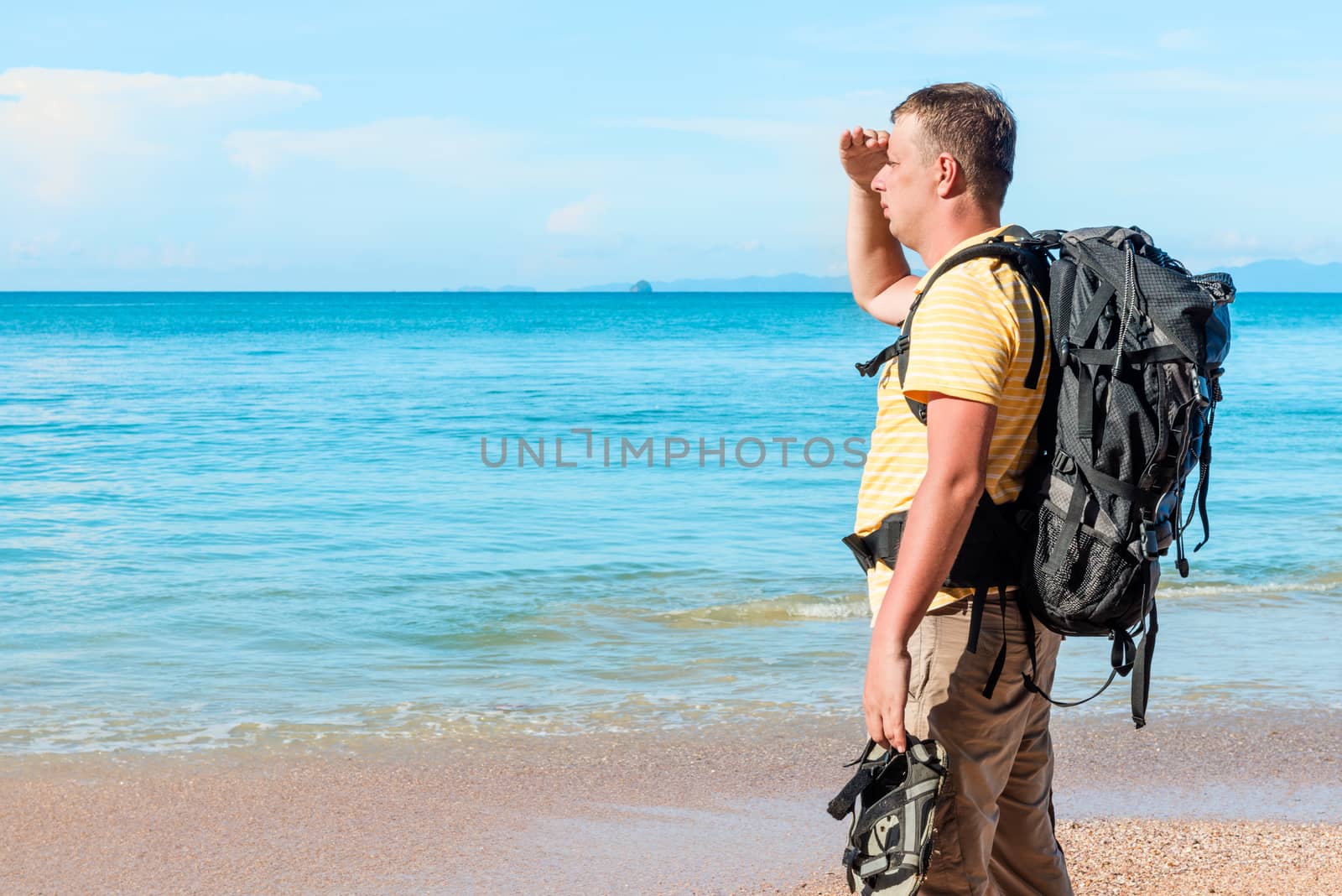 man tourist on holiday on a hike enjoys the sea