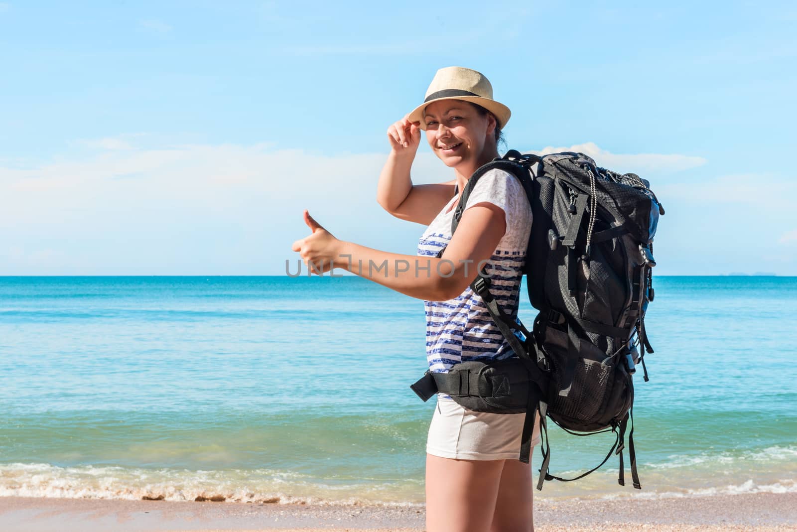 young female tourist with a backpack happy on the beach in Thailand