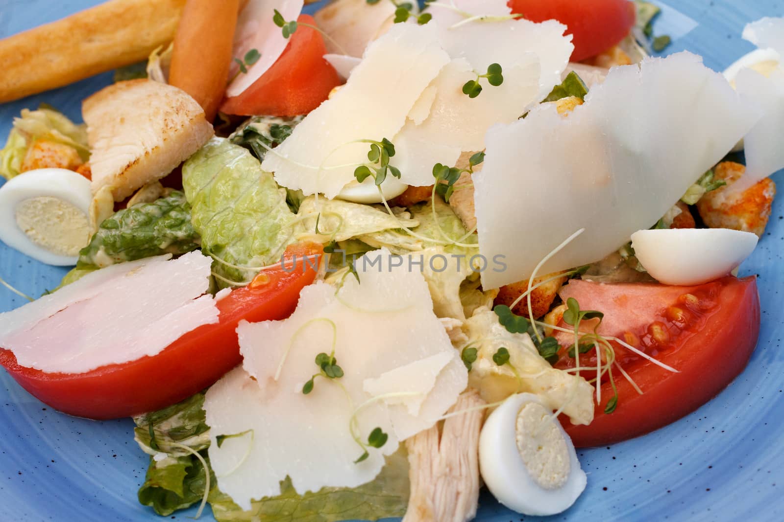 Fresh salad of chicken with vegetables and cheese, on a blue background by fogen