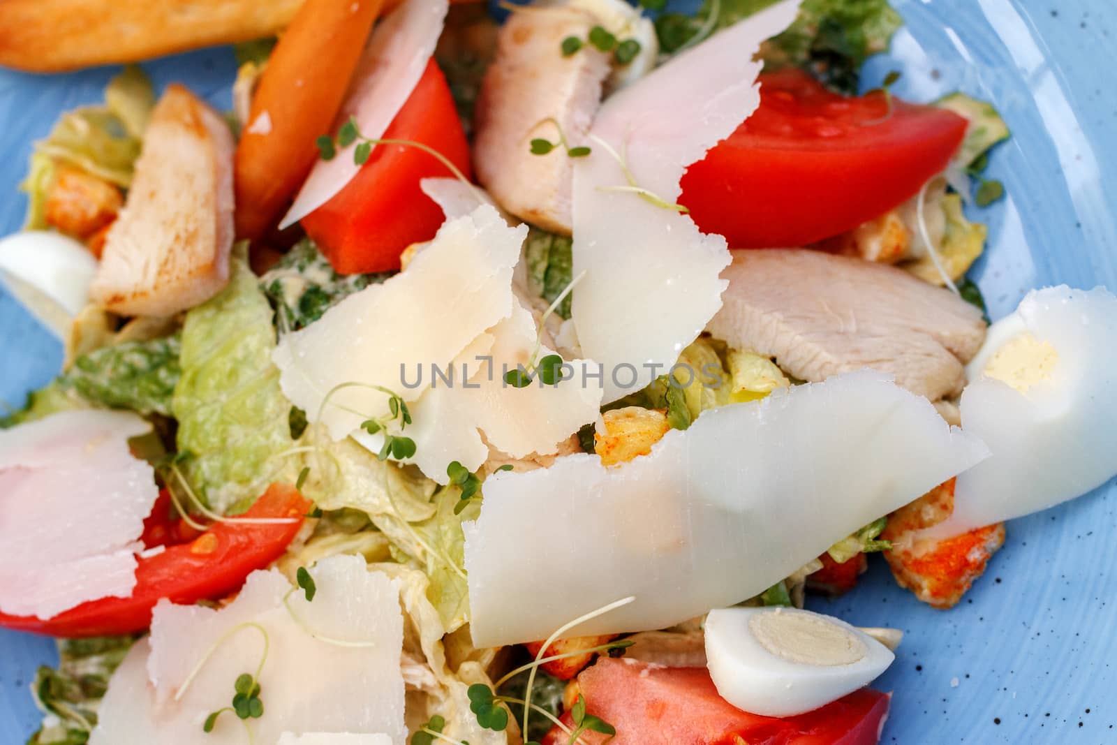 Fresh salad of chicken with vegetables and cheese, on a blue background