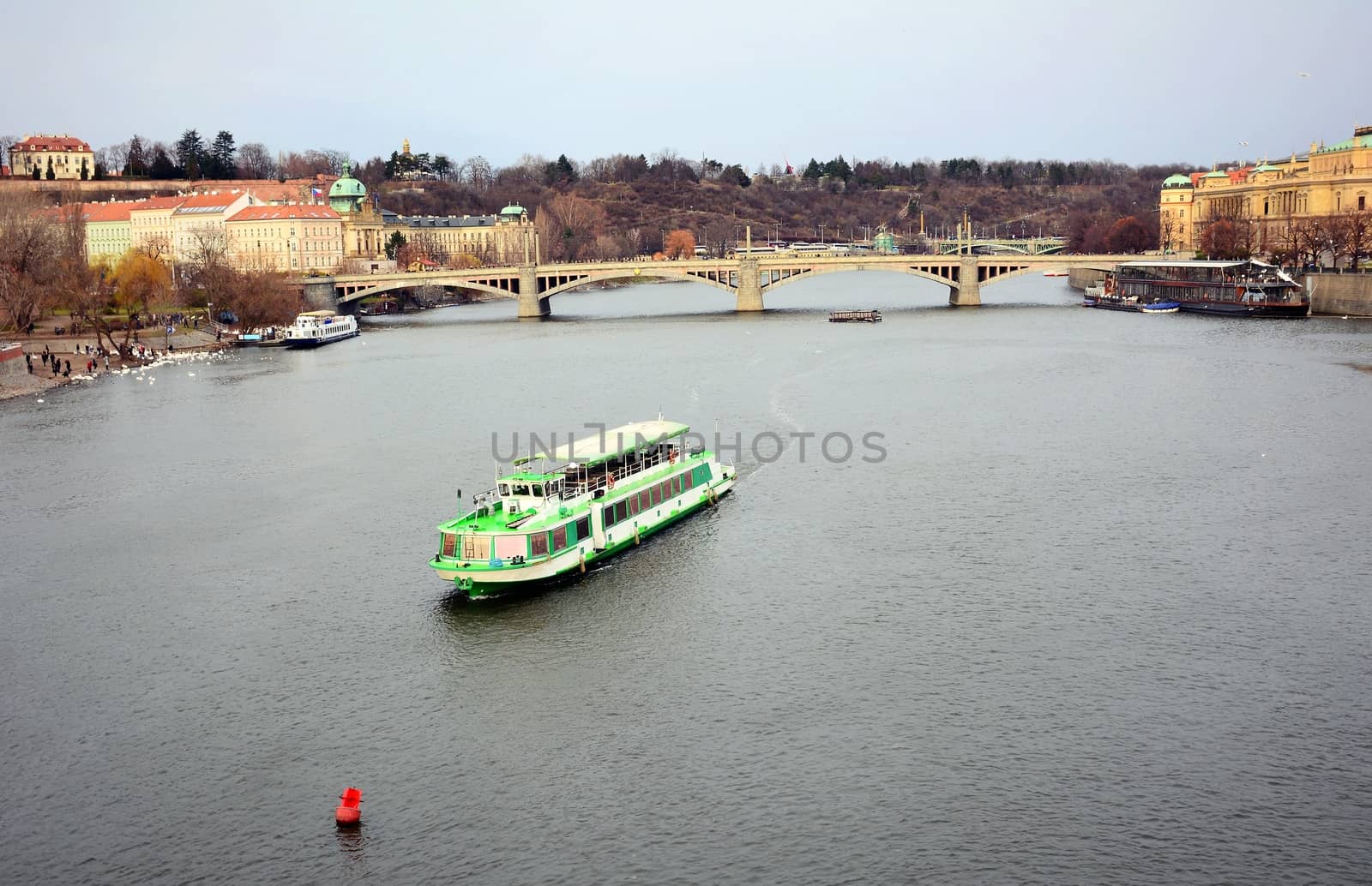 View of the Vltava river with tourist ship and Prague Castle above in old Prague town center.