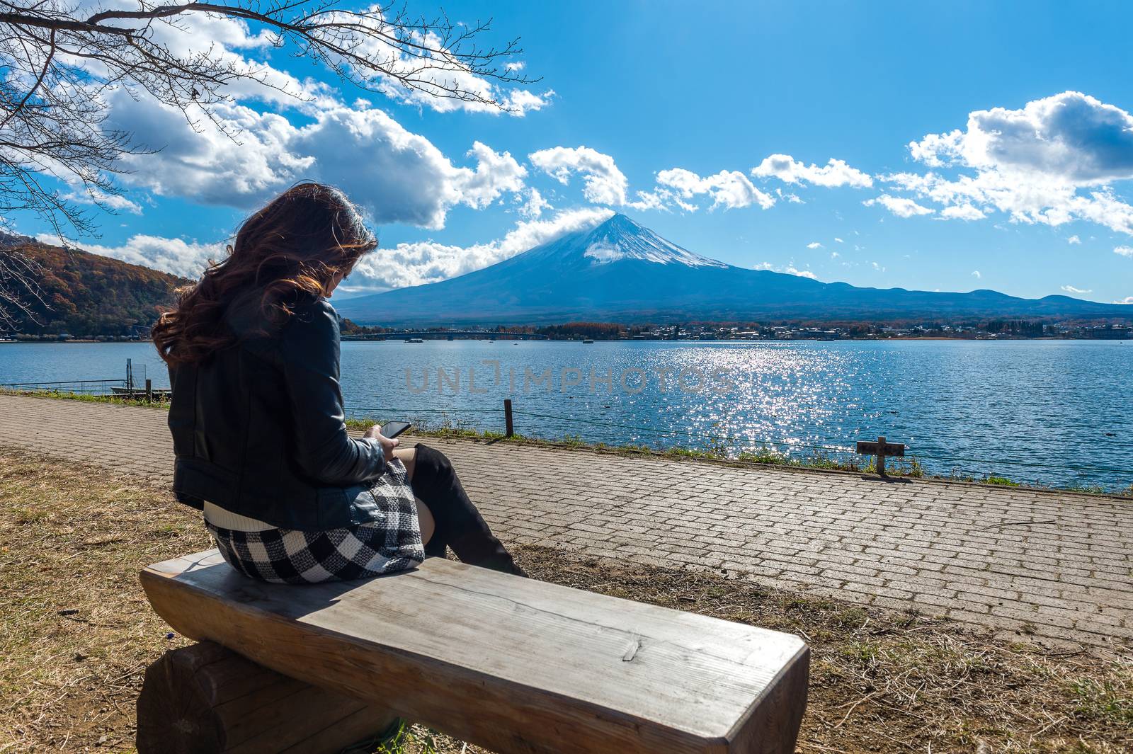 Woman sitting on a bench at kawaguchiko lake, Japan. View of fuji mountains. by gutarphotoghaphy
