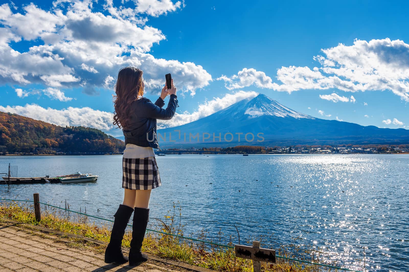 Woman use mobile phone take a photo at Fuji mountains, Kawaguchiko lake in Japan.