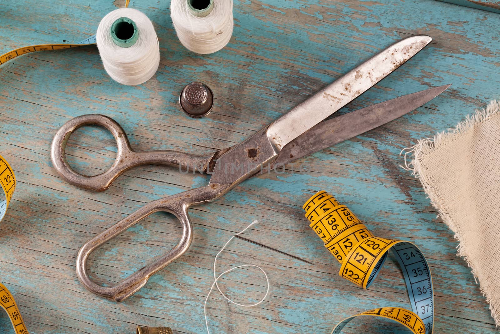 Retro sewing accessories - scissors, tape measure, thread on blue wooden background