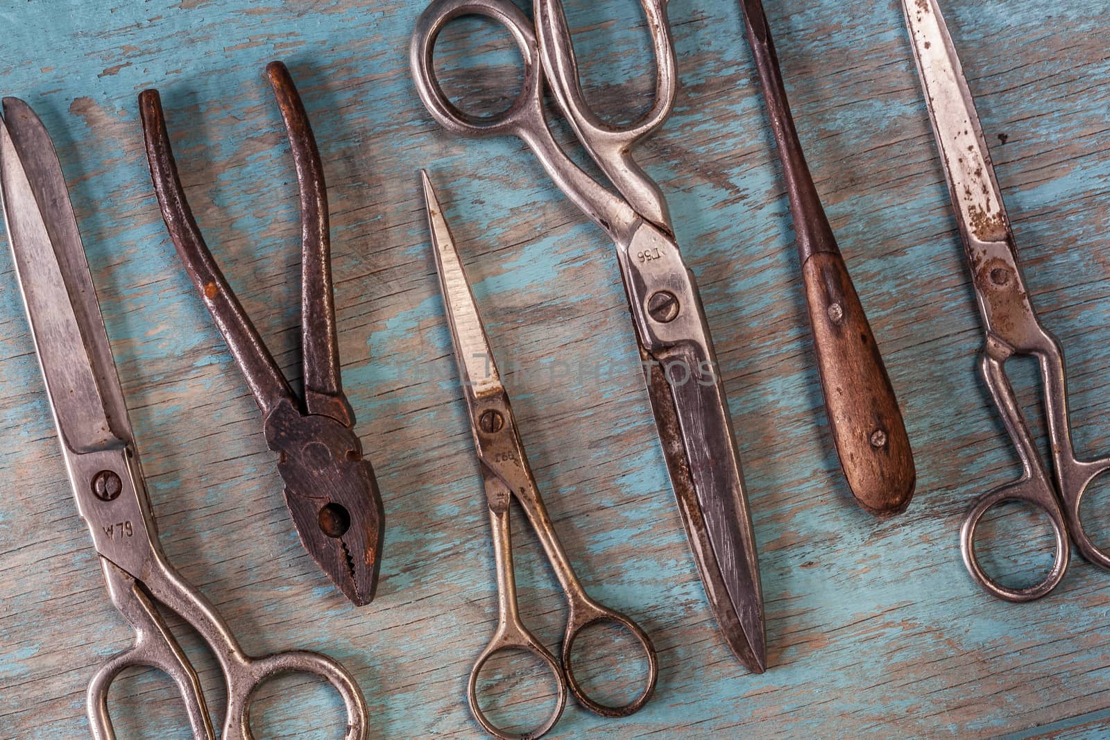 Top view on a collection of vintage tools on a blue wooden background: scissors, pliers, screwdriver. Repairing, craftsmanship and handwork concept, flat lay.