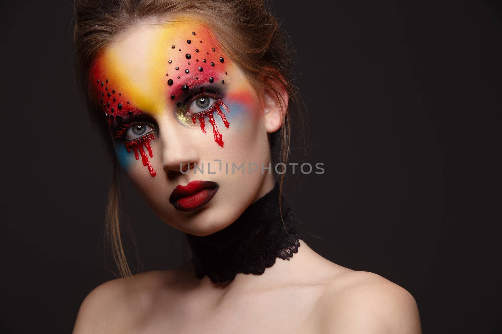 Portrait of young and beauty female model with creative makeup, bloody eyes and black rhinestones