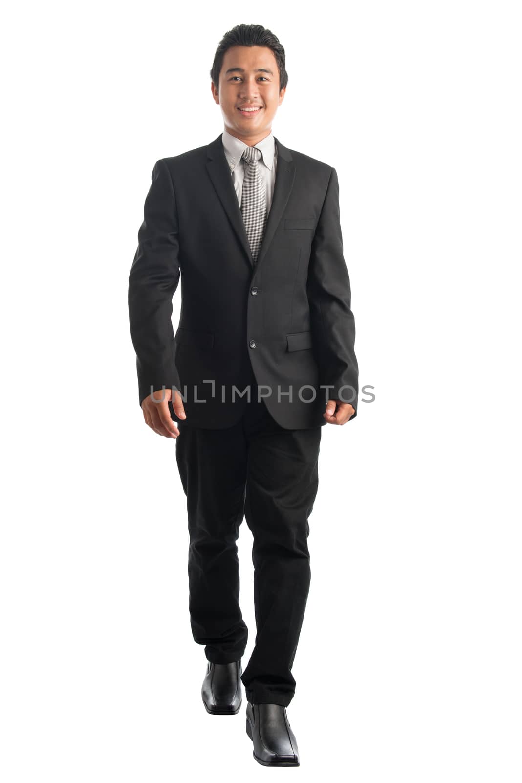 Full body front view portrait of handsome young Southeast Asian businessman walking, isolated on white background. 