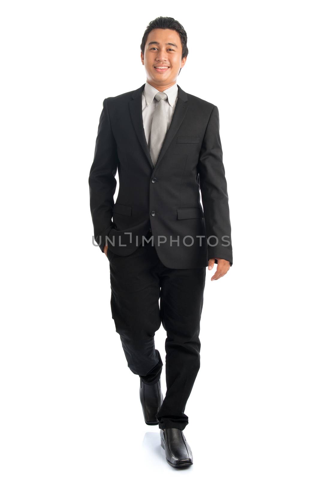 Full length front view portrait of handsome young Southeast Asian businessman walking, isolated on white background. 