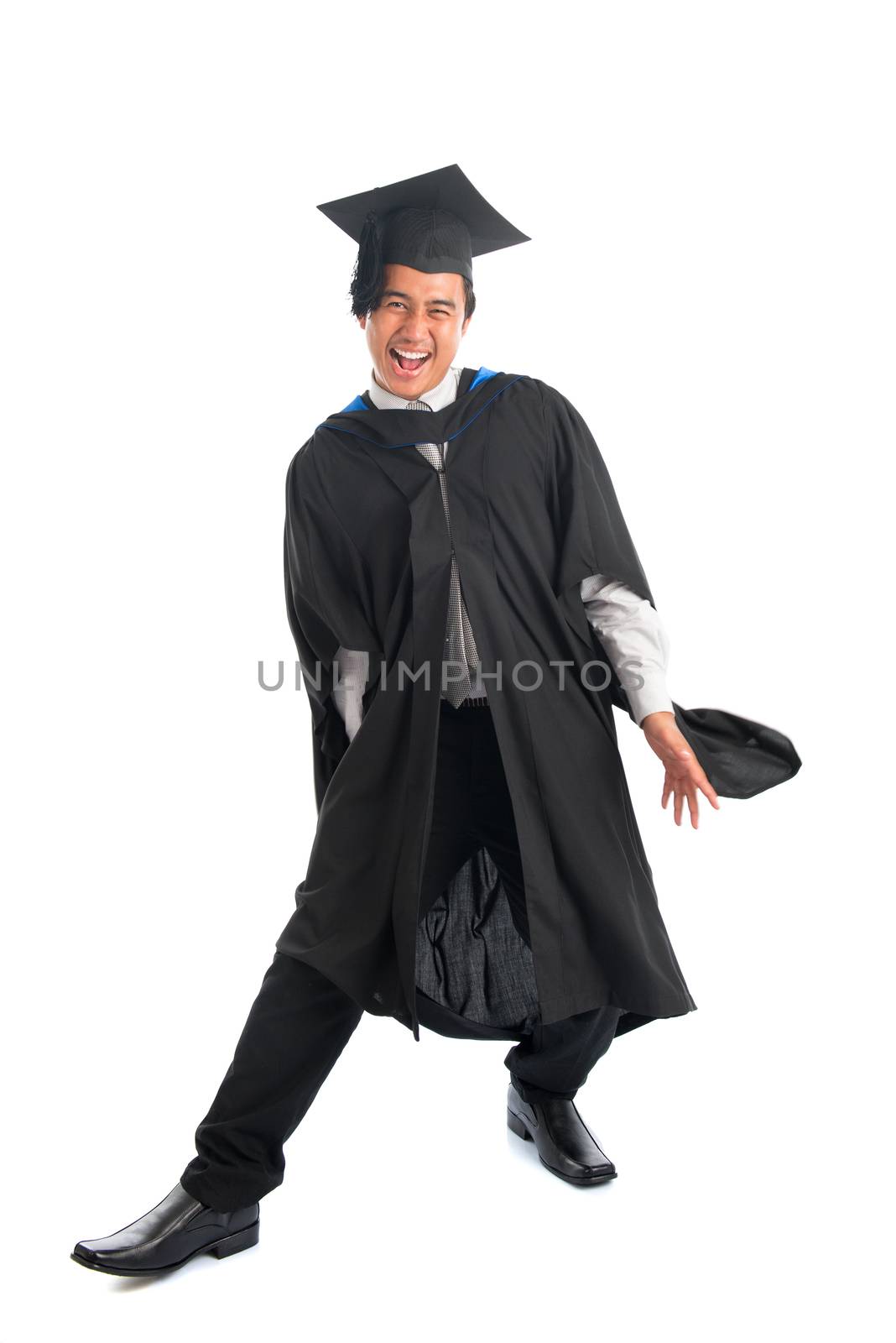 Full body excited Asian male university student in graduation gown jumping high, isolated on white background.