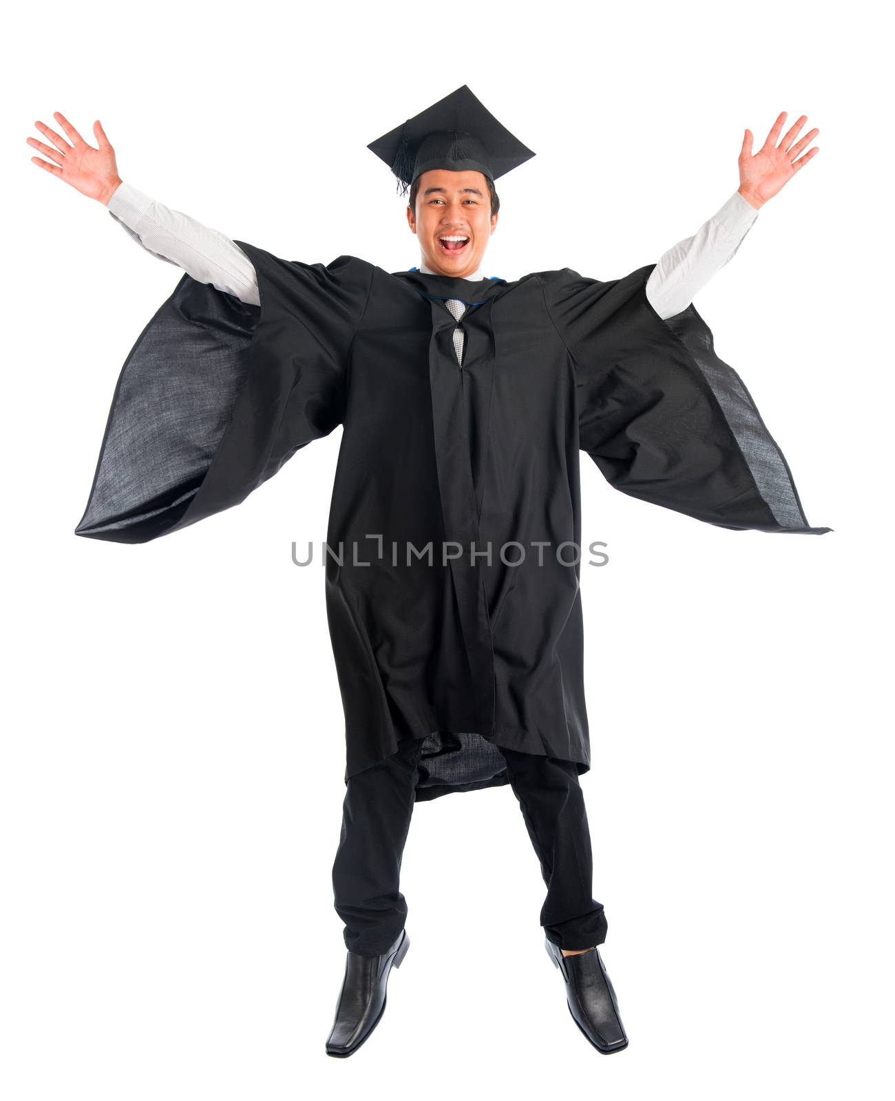 Full body excited Asian young male university student in graduation gown jumping high, isolated on white background. Good looking Southeast model.