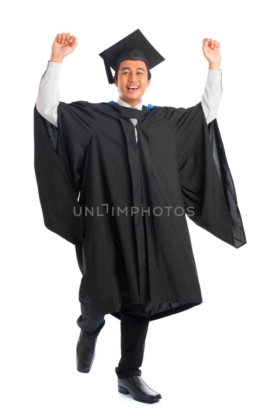 Full body excited handsome Asian male university student in graduation gown jumping high, isolated on white background. Good looking Southeast model.