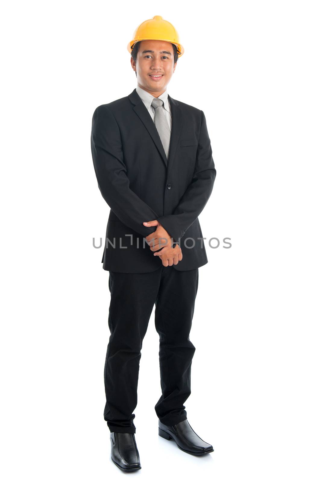 Portrait of full body attractive Southeast Asian engineer with yellow hard hat smiling, standing isolated on white background.