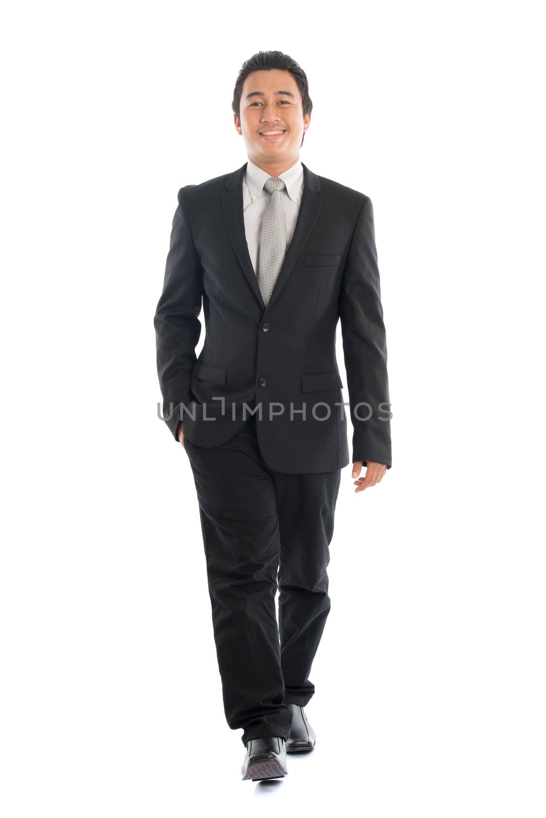 Full body front view portrait of young Southeast Asian businessman walking, isolated on white background. 