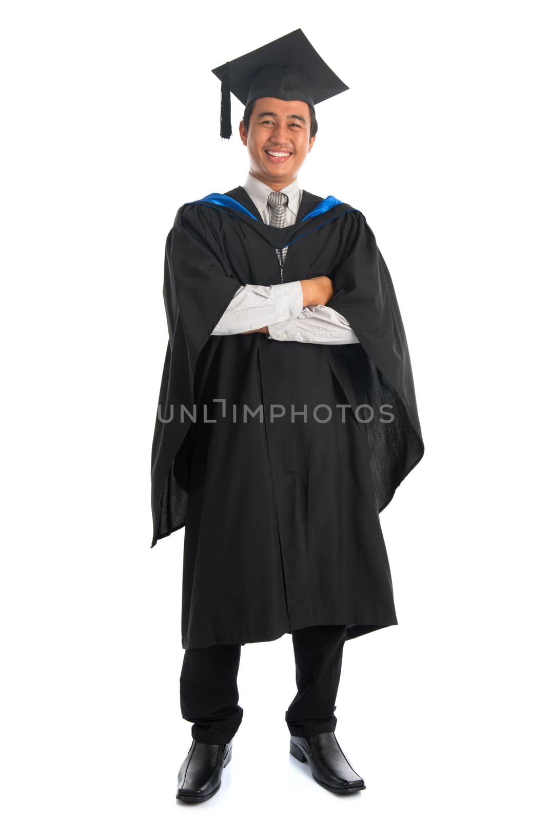 Full body happy arms crossed Asian male university student in graduation gown smiling, isolated on white background. Good looking Southeast model.