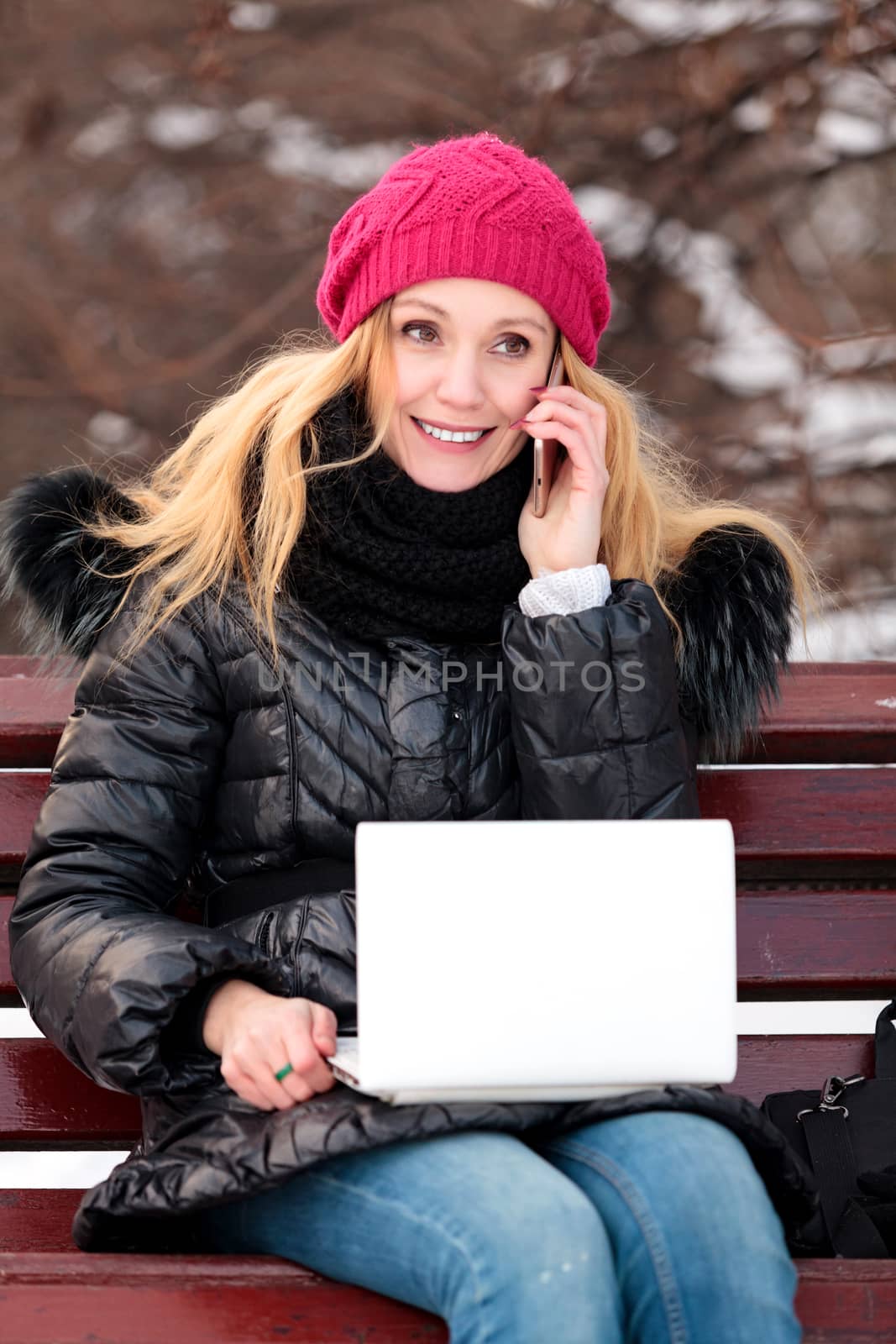 Portrait of smiling woman sitting on a bench in a park talking o by Nobilior