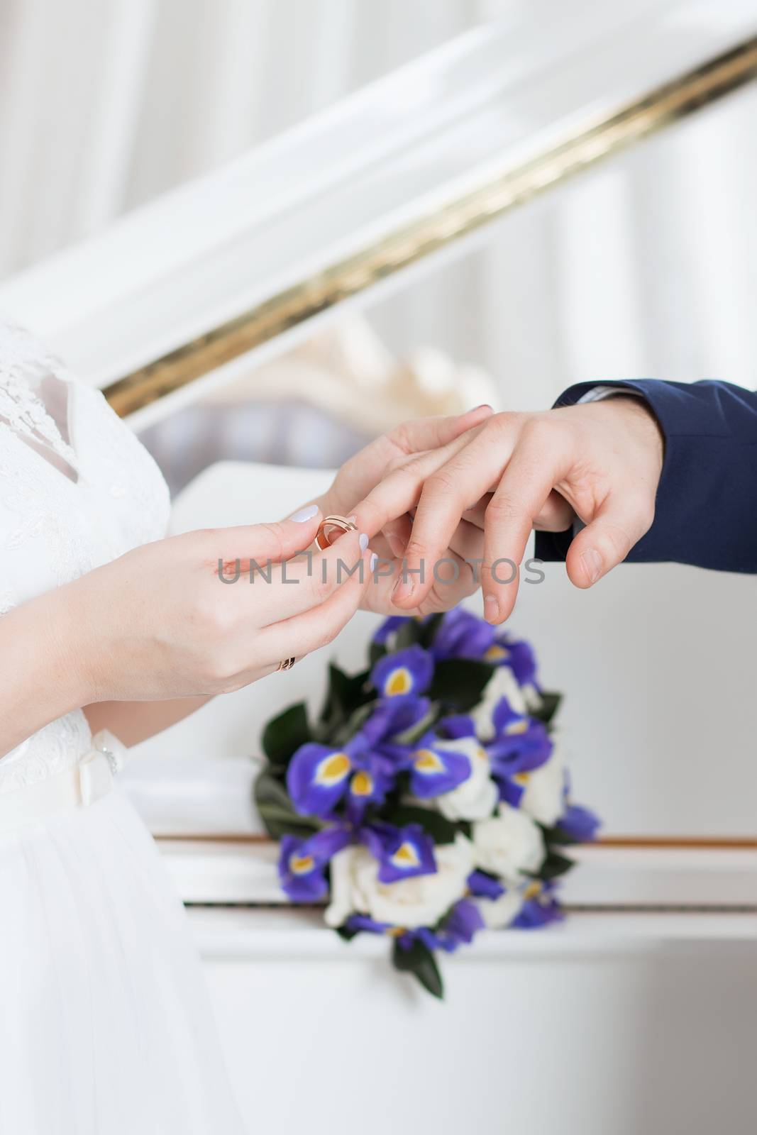 Wedding day. The groom places the ring on the bride's hand.