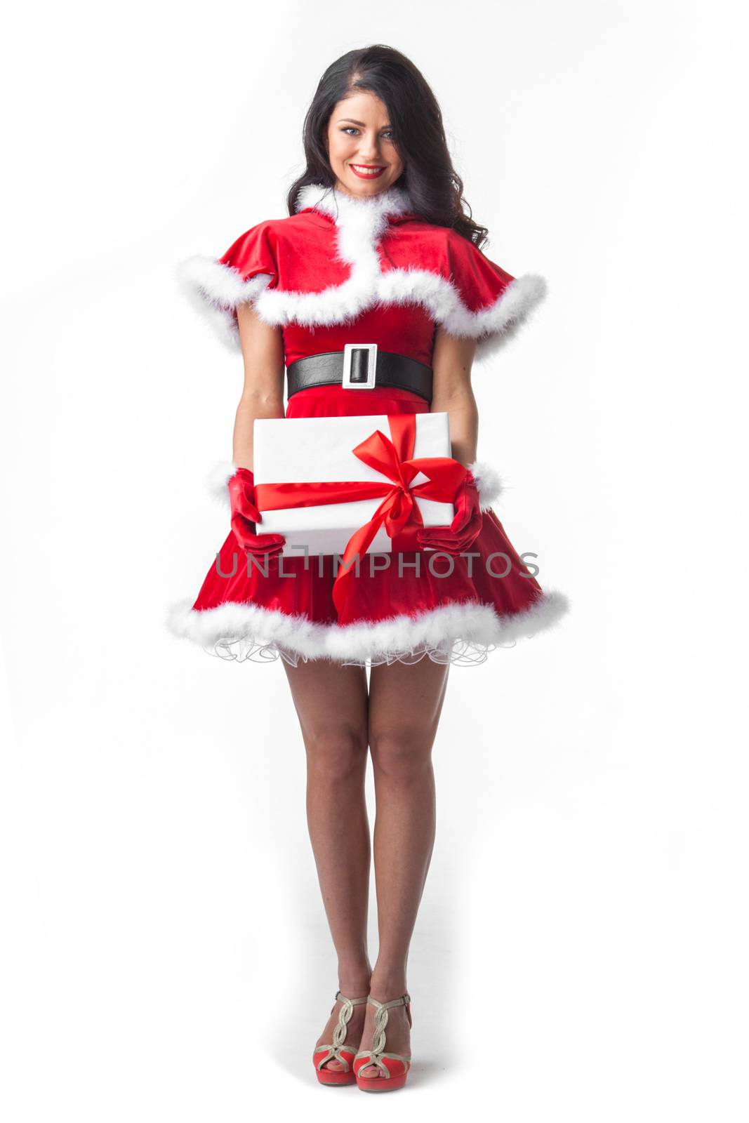 Beautiful young woman in Santa dress celebrating Christmas holding gift box