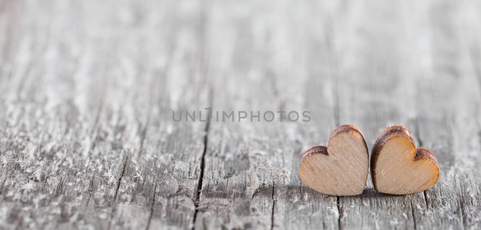 Two small wooden hearts on old cracked wood background