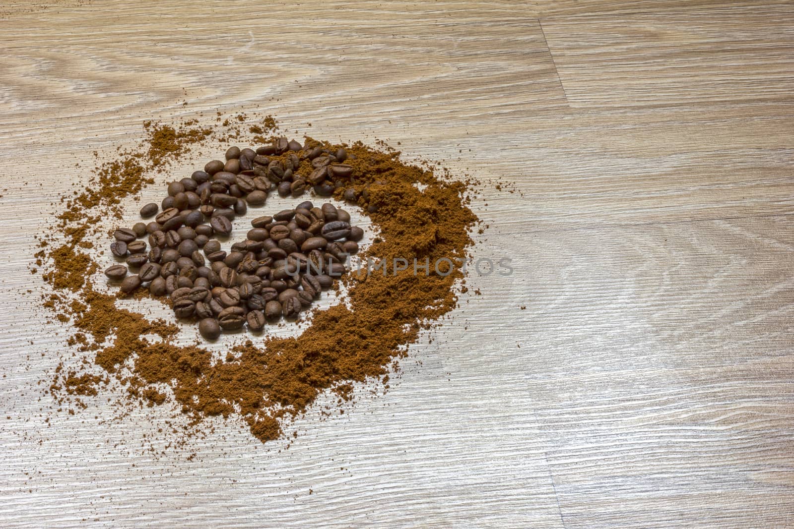 Coffee beans and ground coffee on a wooden table like a spiral.   by EdVal