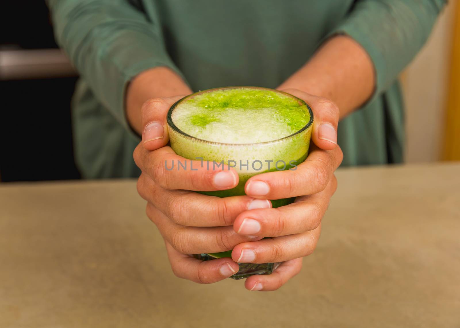 Woman holding a glass of green juice. Preparing a detox juice. 