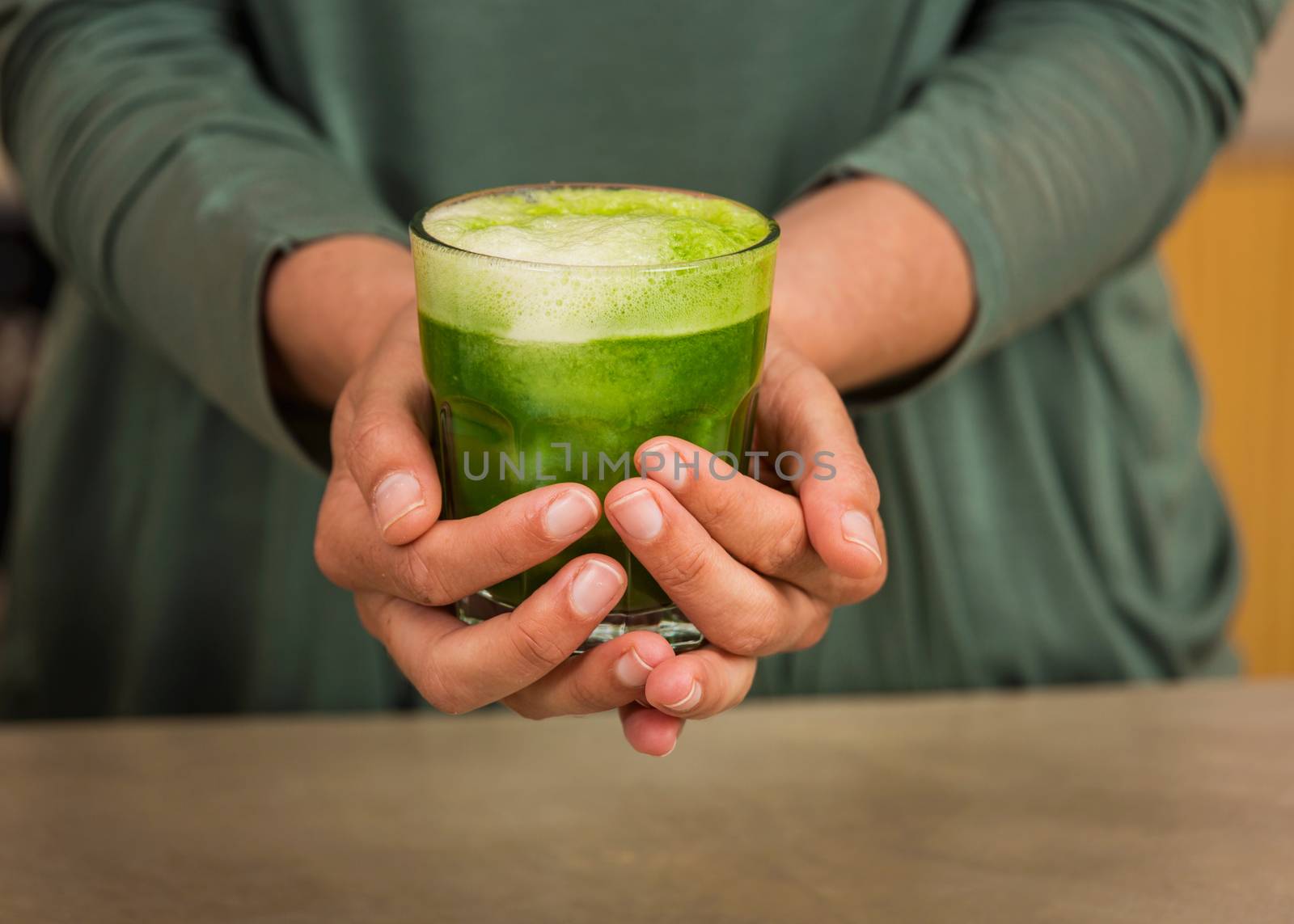 Woman holding a glass of green juice. Preparing a detox juice. 