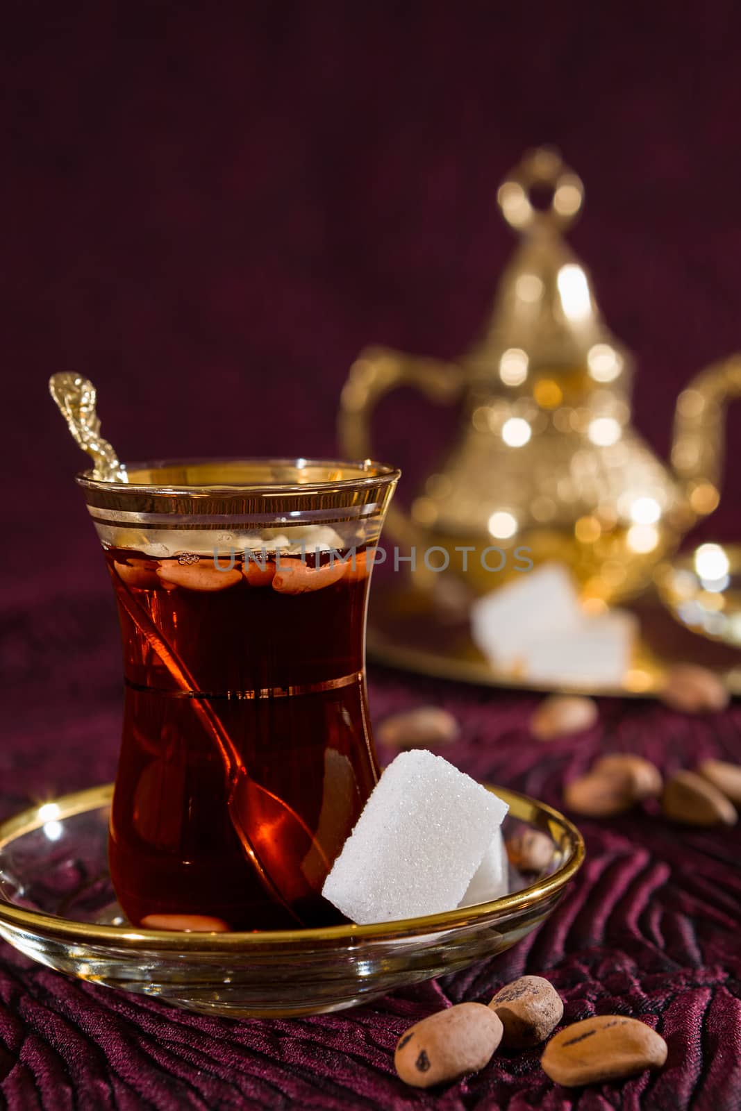 Closeup of Tunisian tea in traditional glass with sugar cube and pine nuts