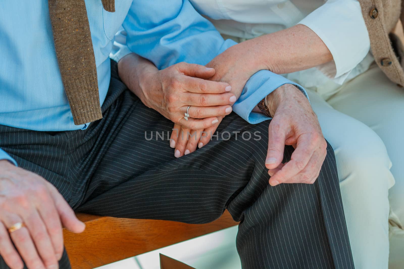 Cropped shot of elderly couple holding hands while sitting together