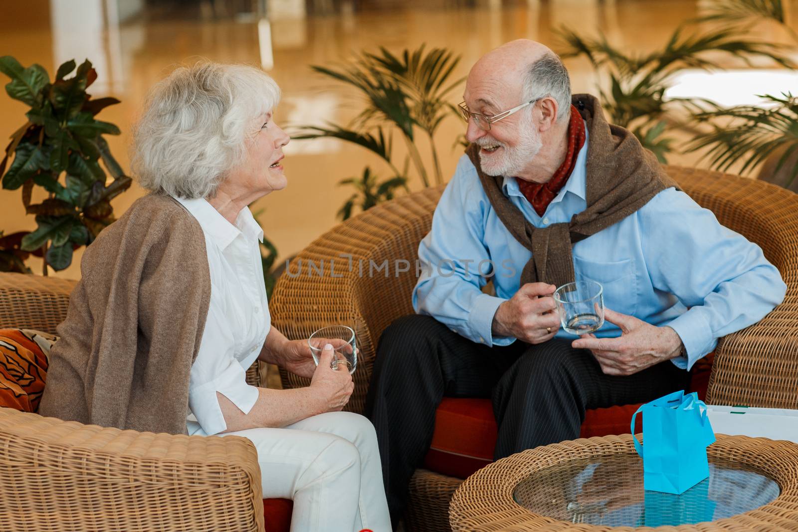Elderly couple in cafe sitting, smiling and talking to each other