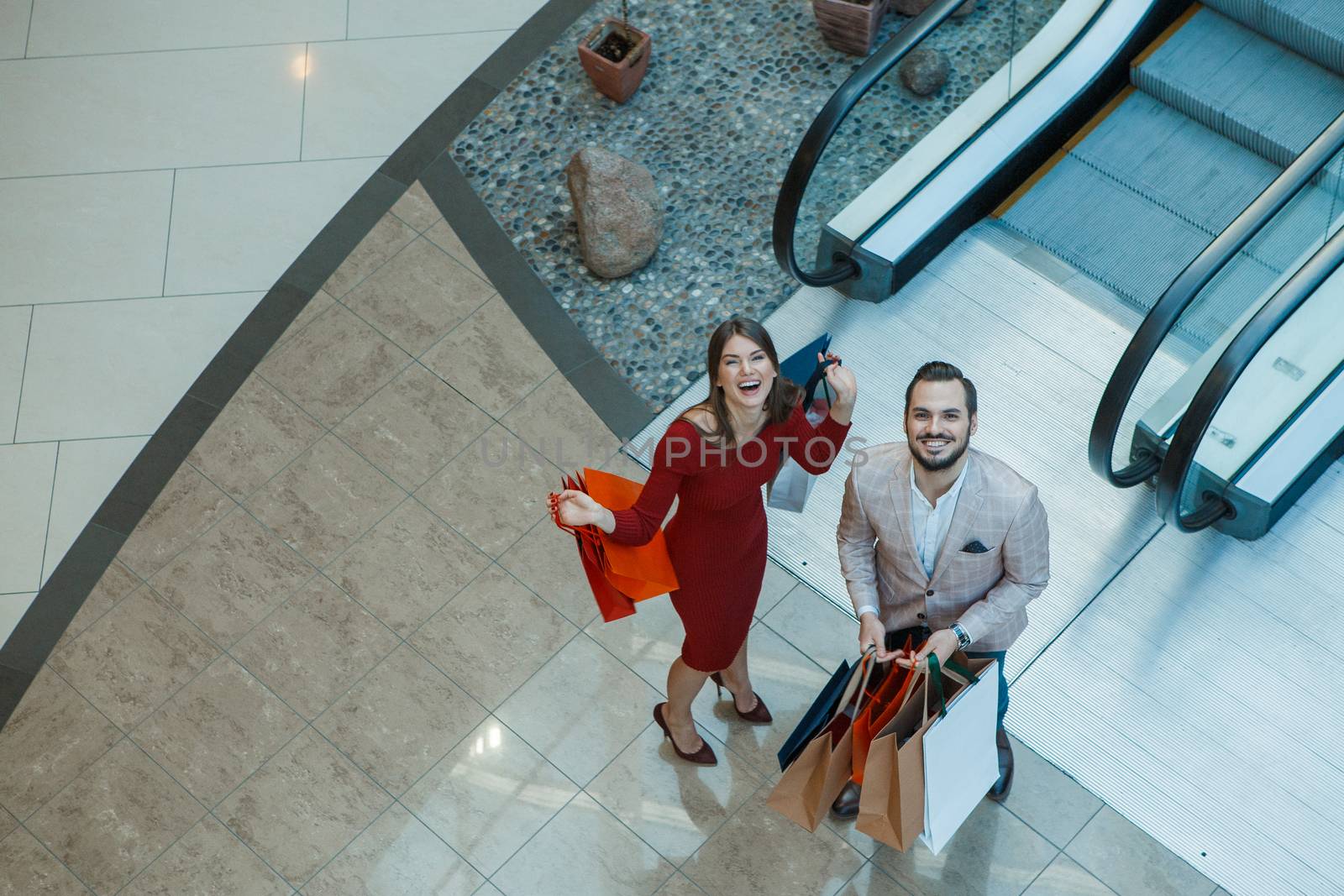 Happy beautiful young couple with shopping bags in mall