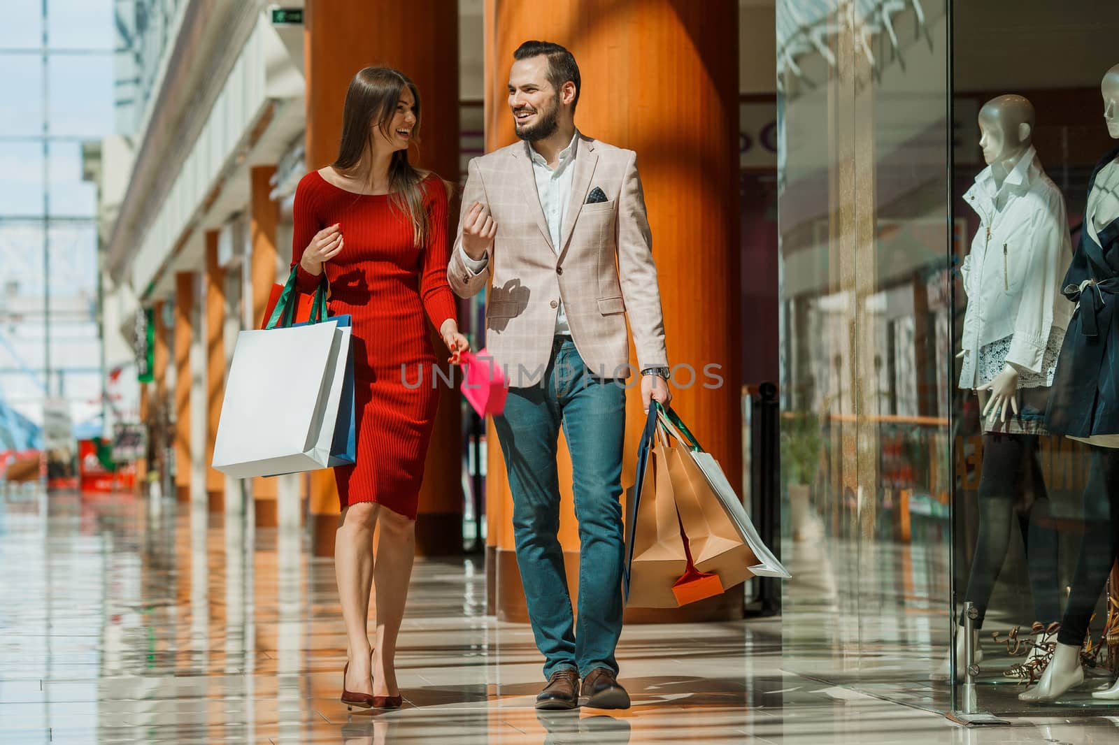 Happy beautiful young couple with shopping bags in mall