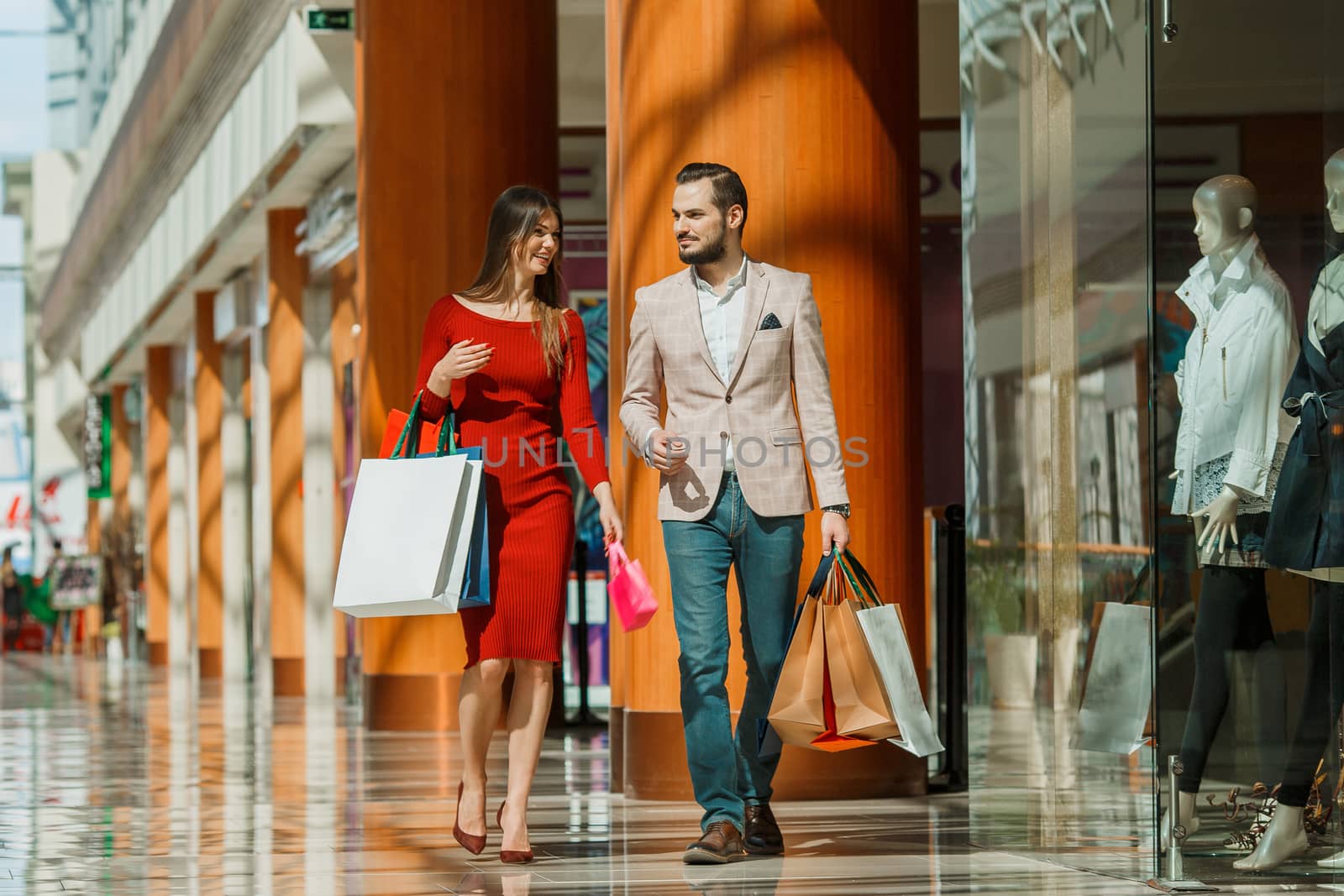 Happy beautiful young couple with shopping bags in mall