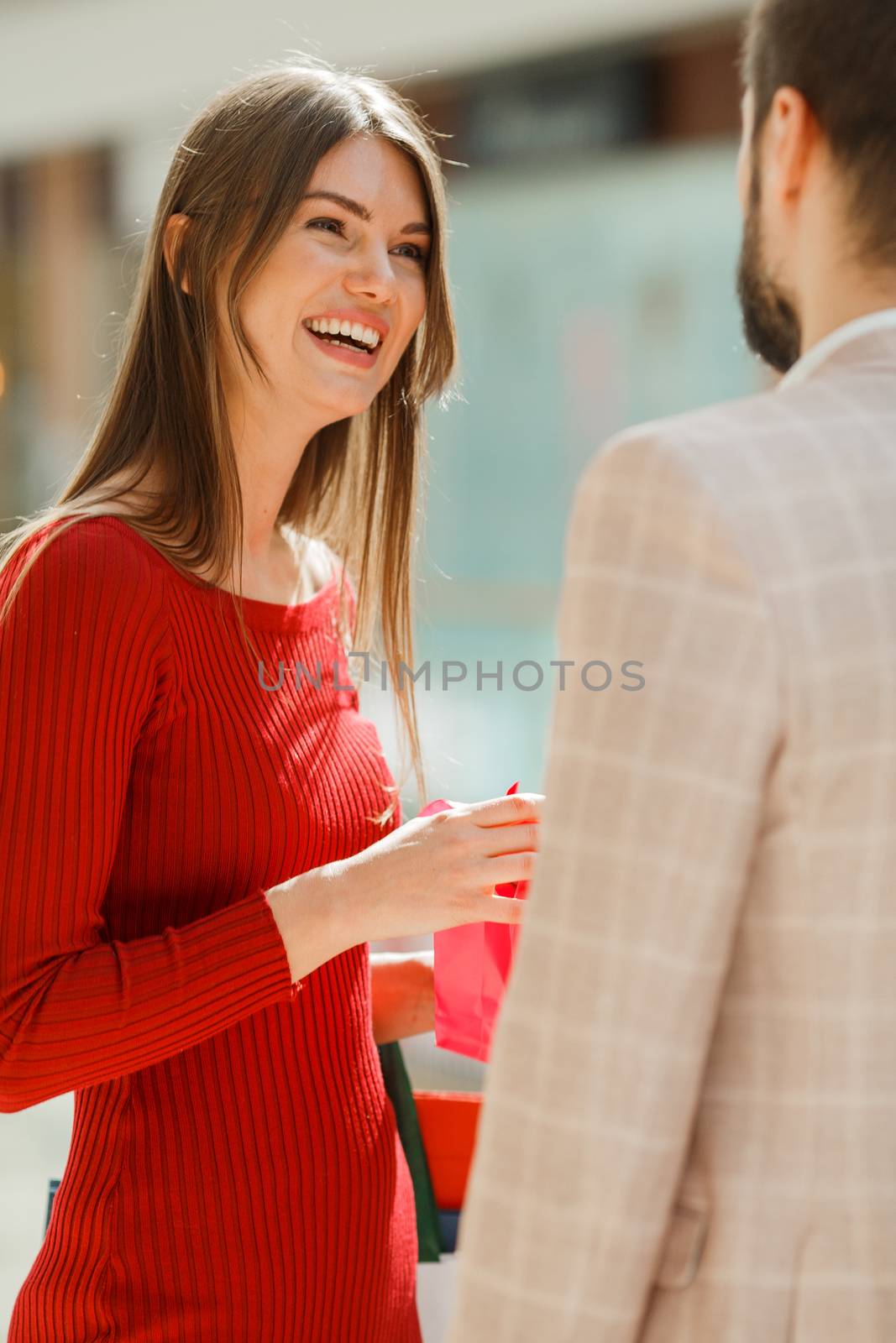 Happy beautiful young couple with gift in shopping mall