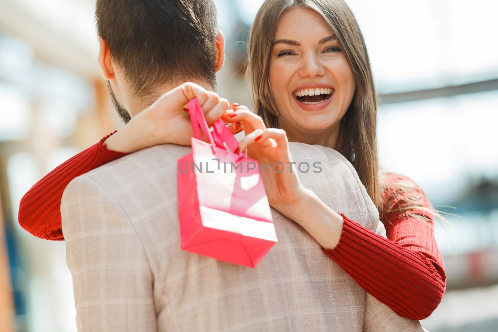 Happy beautiful young couple with gift bag hug in shopping mall
