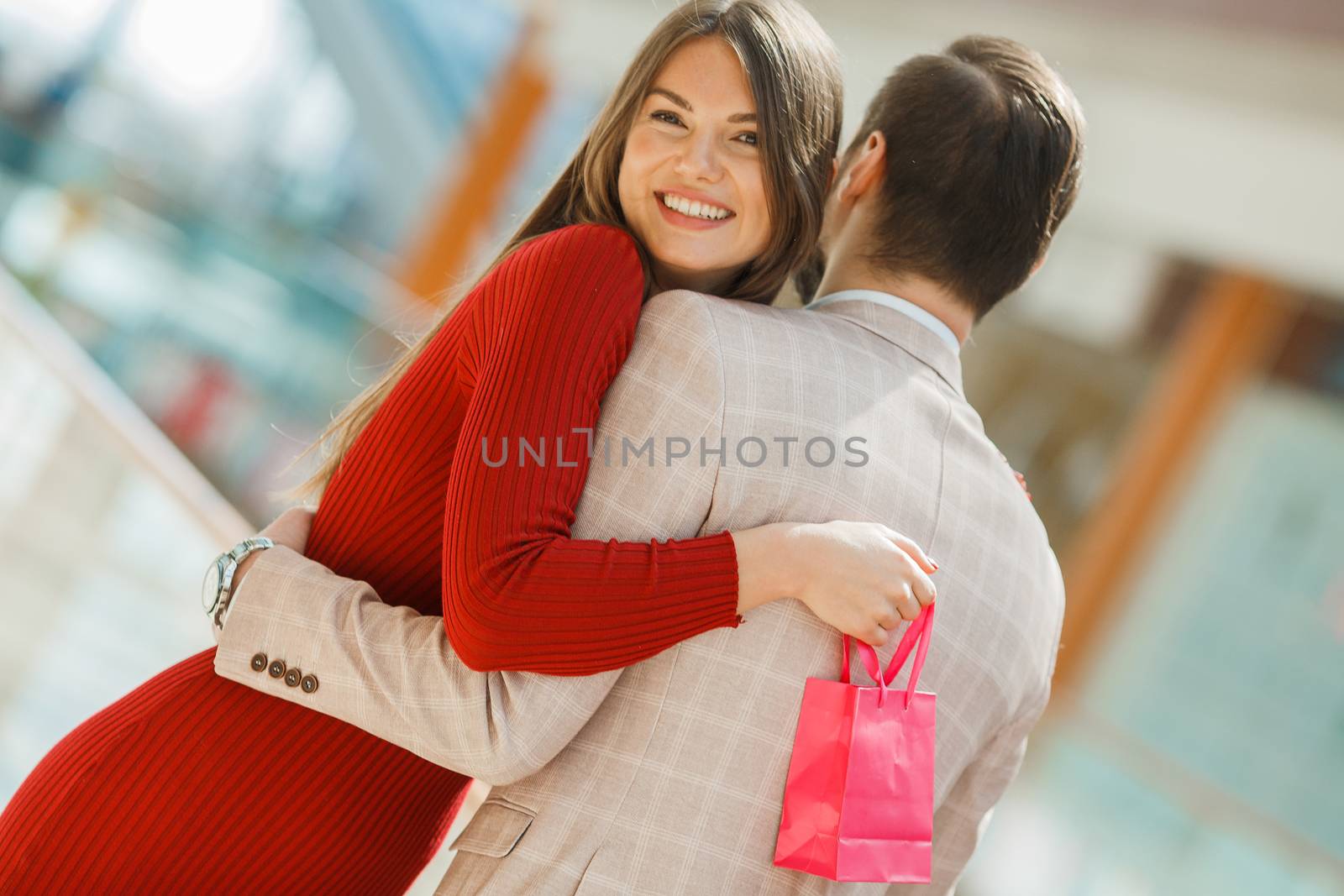 Happy beautiful young couple with gift bag hug in shopping mall