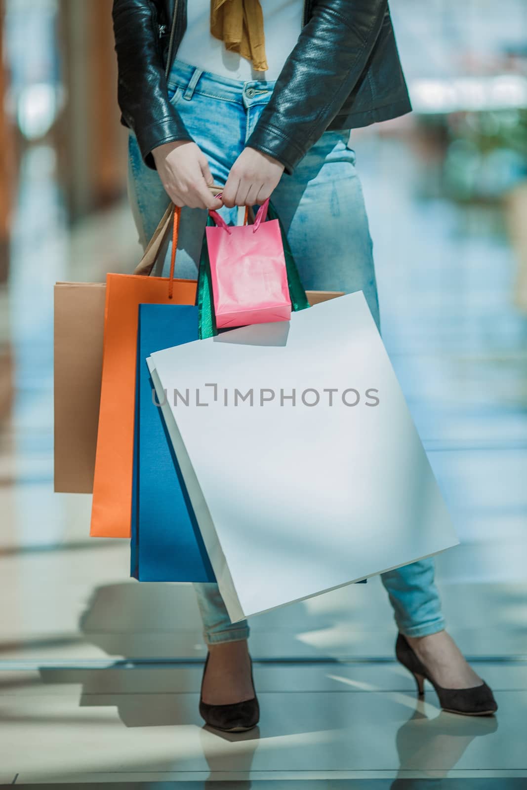 Sale and people - smiling woman with colorful shopping bags over supermarket background