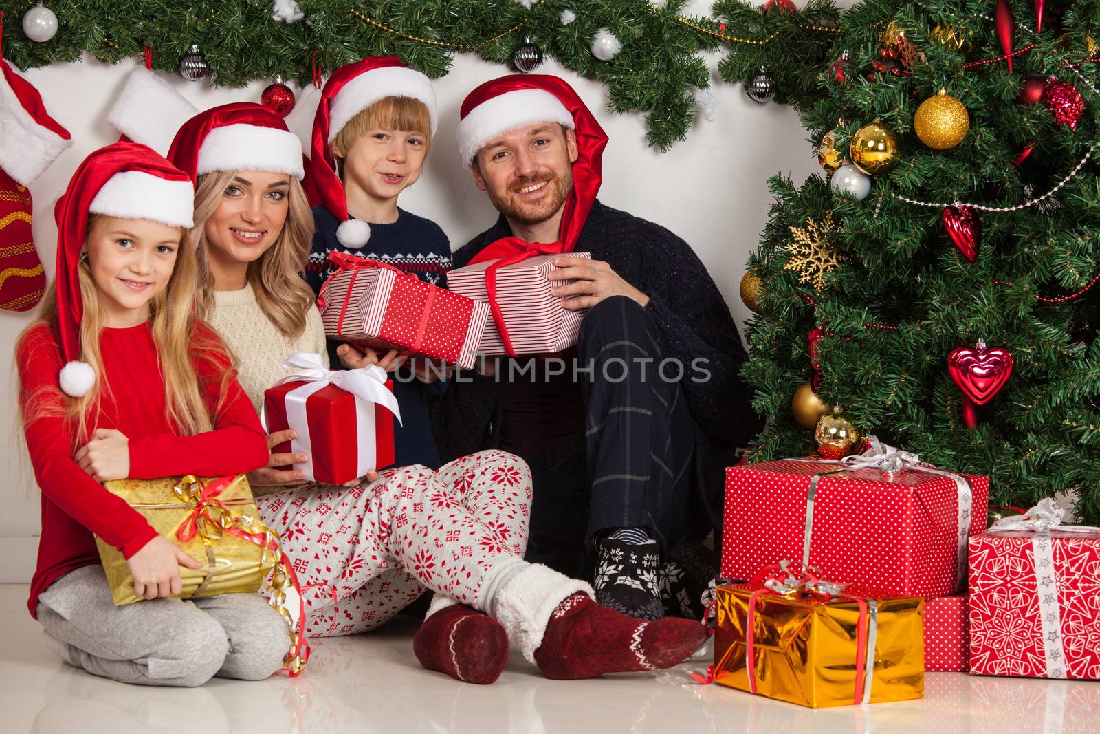 Cheerful family with Christmas gifts sitting near decorated Christmas tree