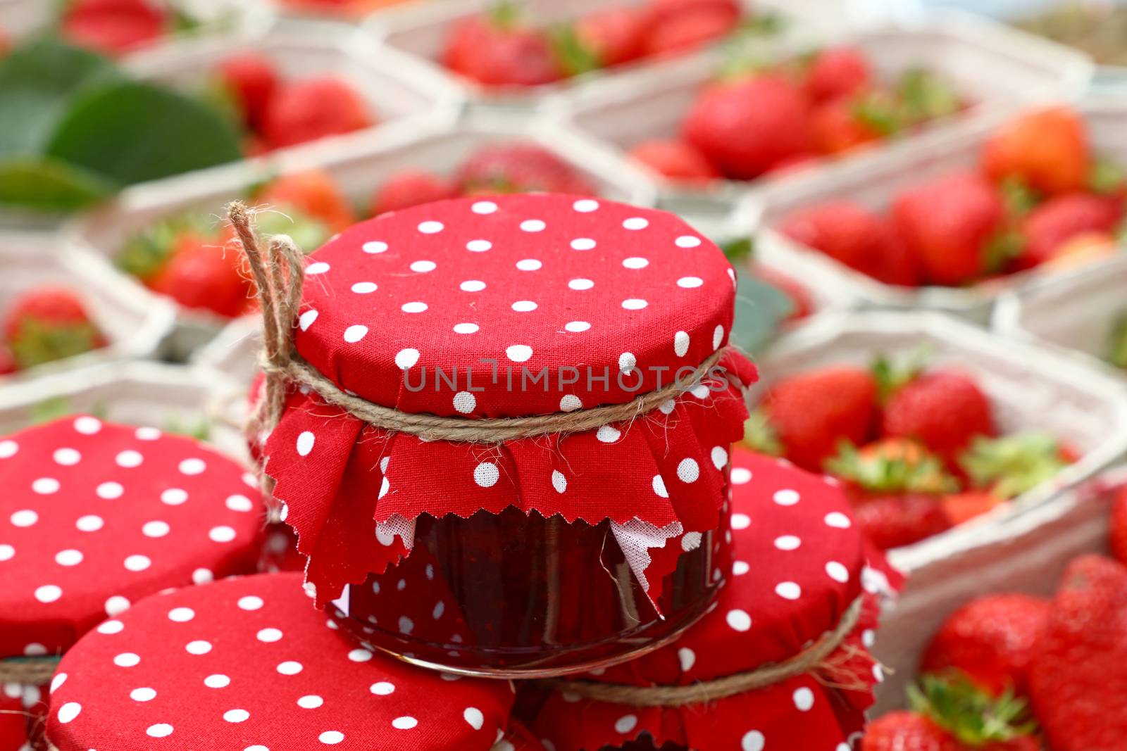 Jars of red jam over fresh strawberries by BreakingTheWalls