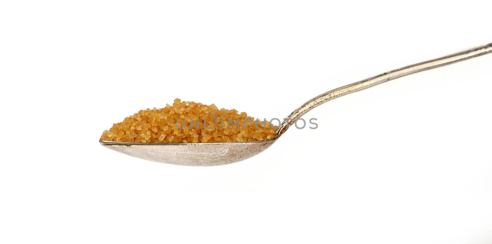 Close up one vintage silver metal spoon full of raw brown cane sugar isolated on white background, low angle side view