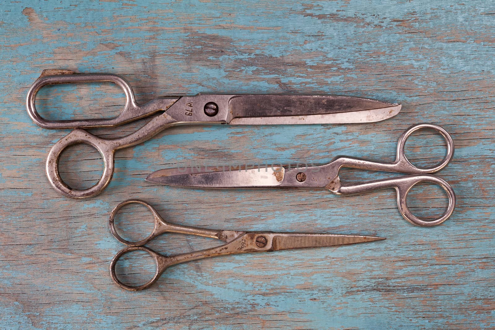 A set of vintage scissors on blue wooden background by igor_stramyk