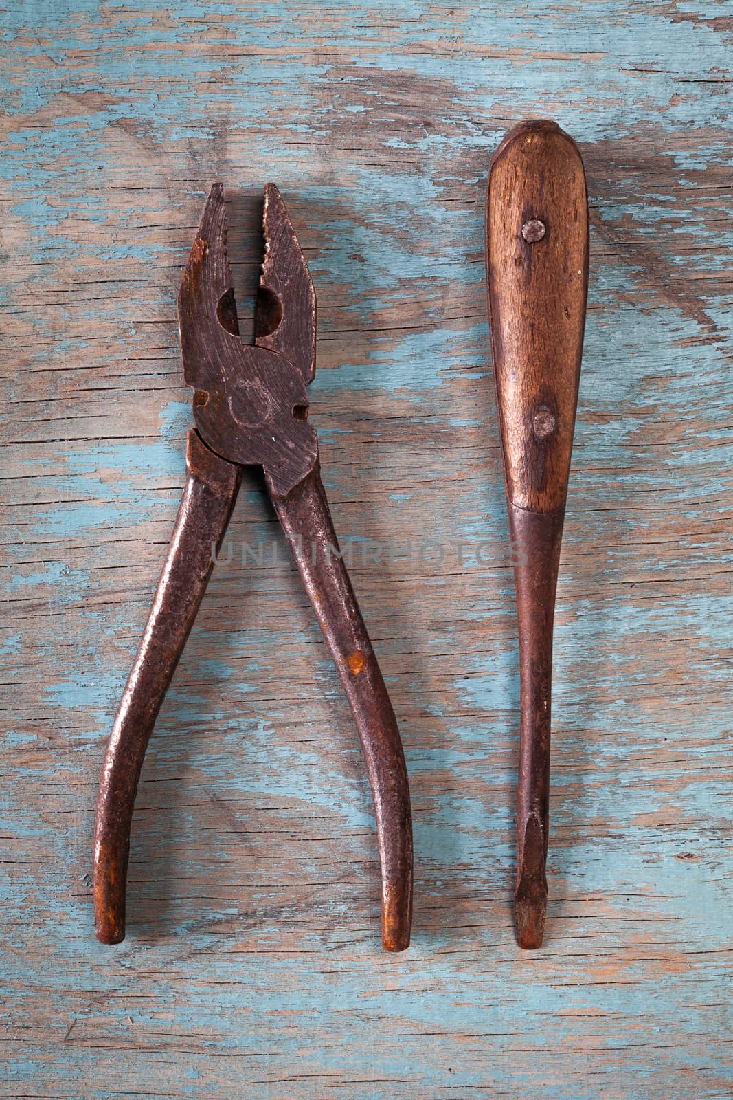 Top view on vintage tools on a blue wooden background: pliers and screwdriver. Repairing, craftsmanship and handwork concept, flat lay.