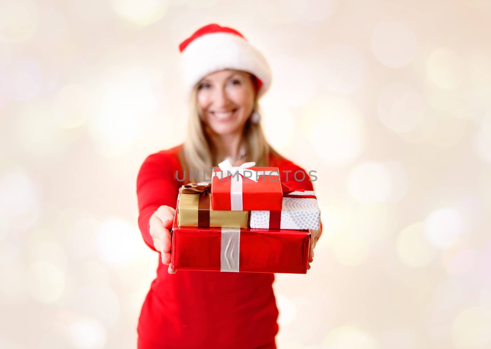 Woman holding a bunch of Christmas presents in her hands with arms extended in an act of giving. Shallow dof to presents only.