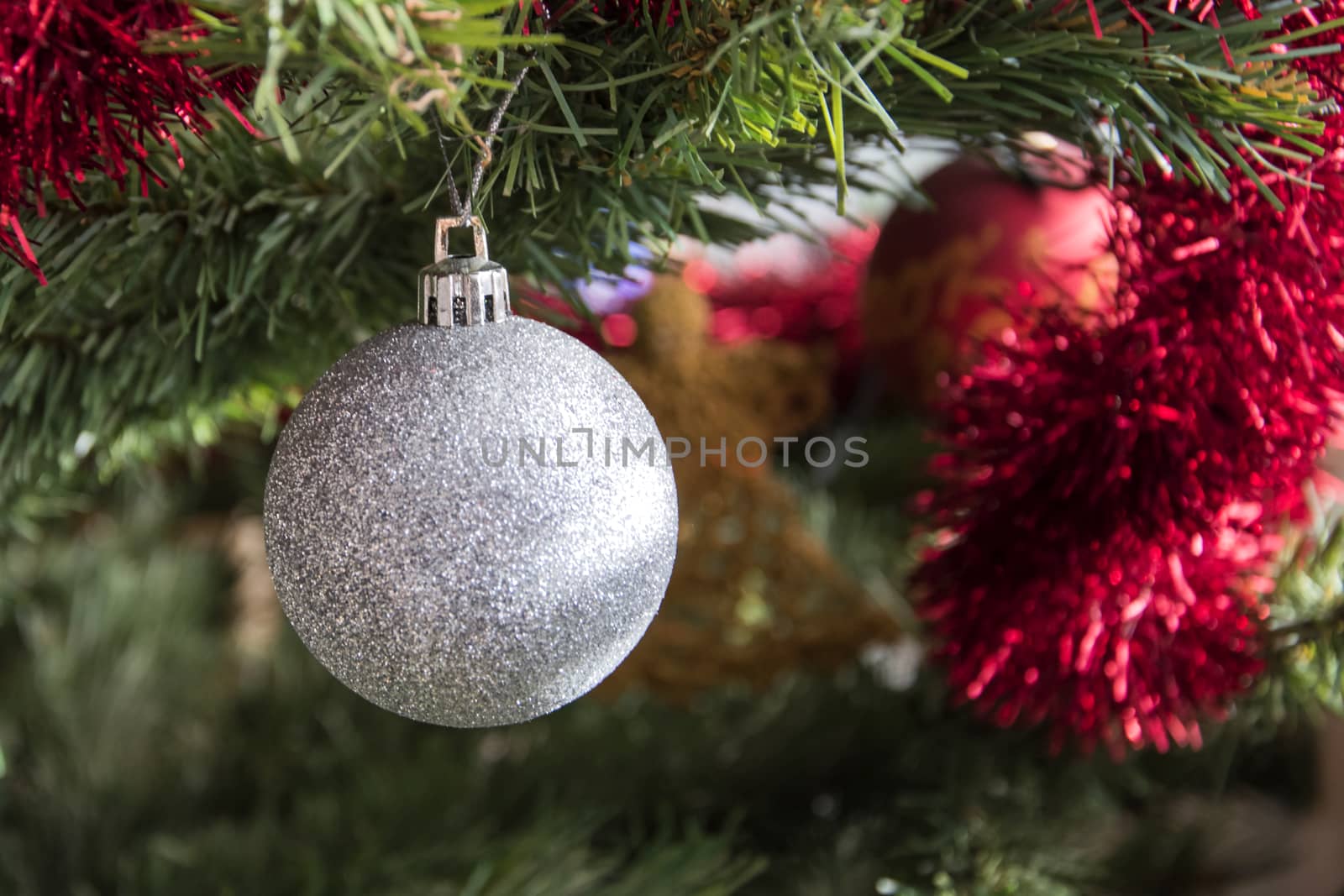 silver bauble ornament hanging on christmas tree. Beautiful close up holiday photo. 
