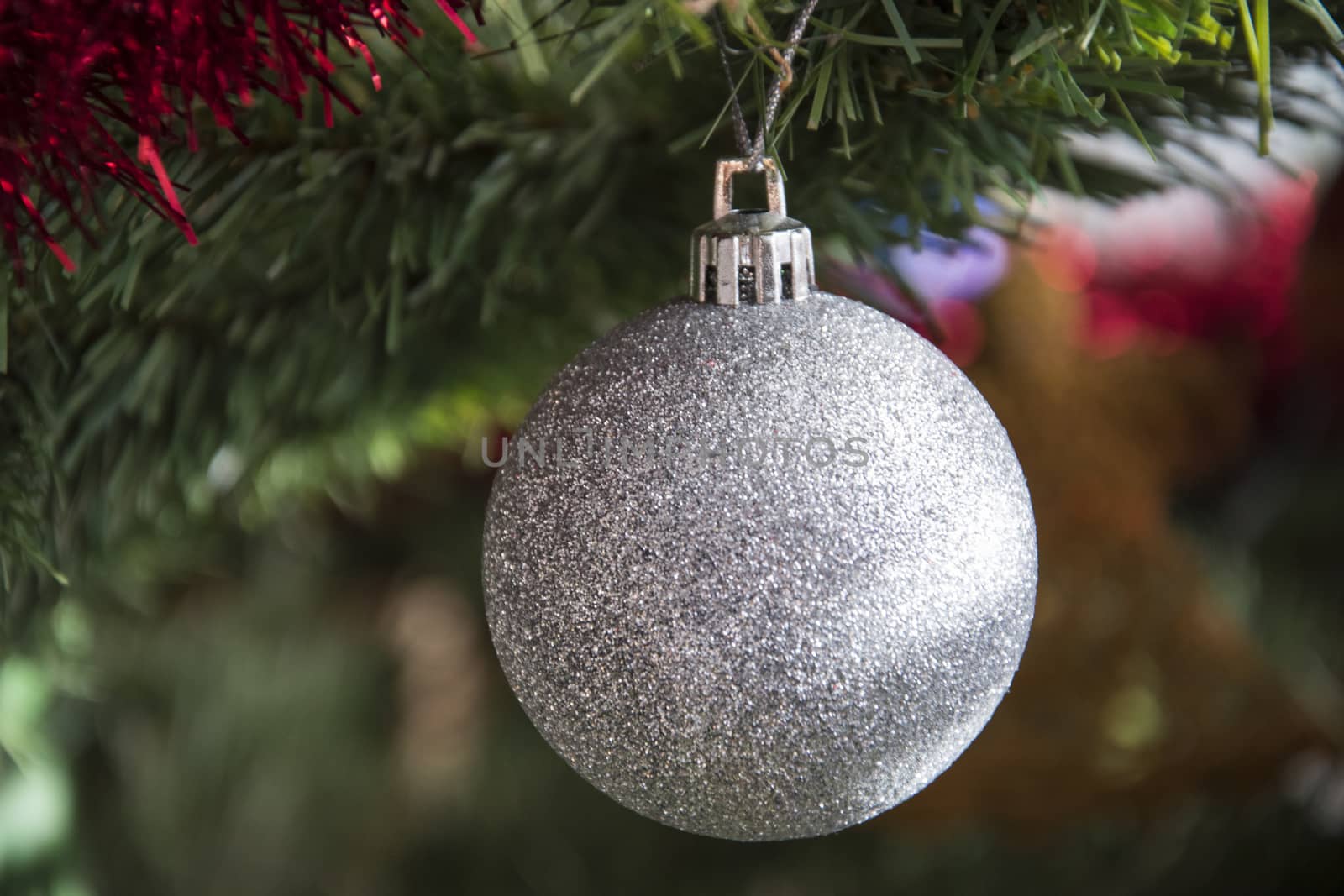 silver bauble ornament hanging on christmas tree. Beautiful close up holiday photo. 
